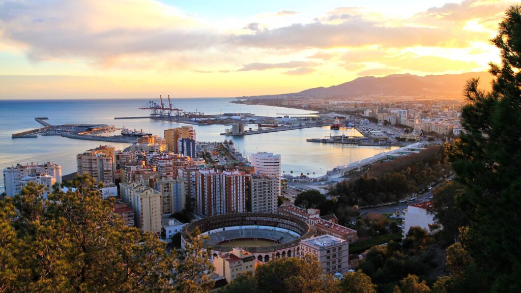 Panoramic view of Malaga featuring sunny beaches, historic architecture, and bustling streets, perfect for those considering relocating to this beautiful Spanish city